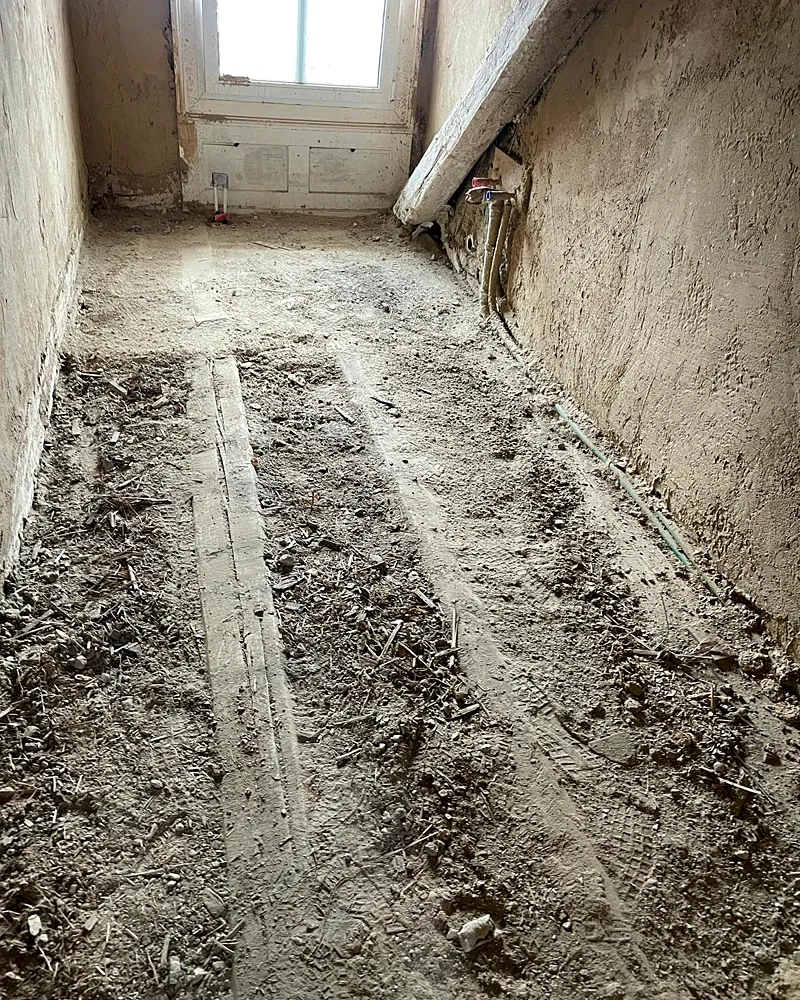 Entkernter Raum mit freigelegtem Boden während der Sanierung