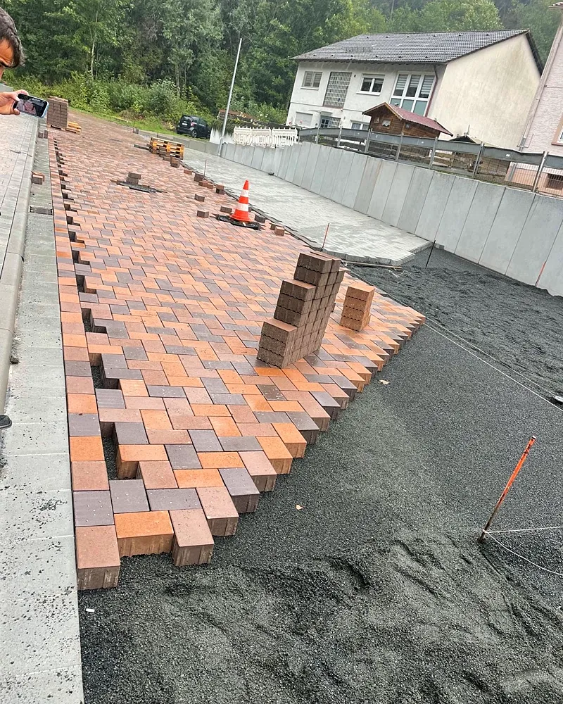 Pflasterverlegung in Arbeit: terracottafarbene Steine im Splittbett