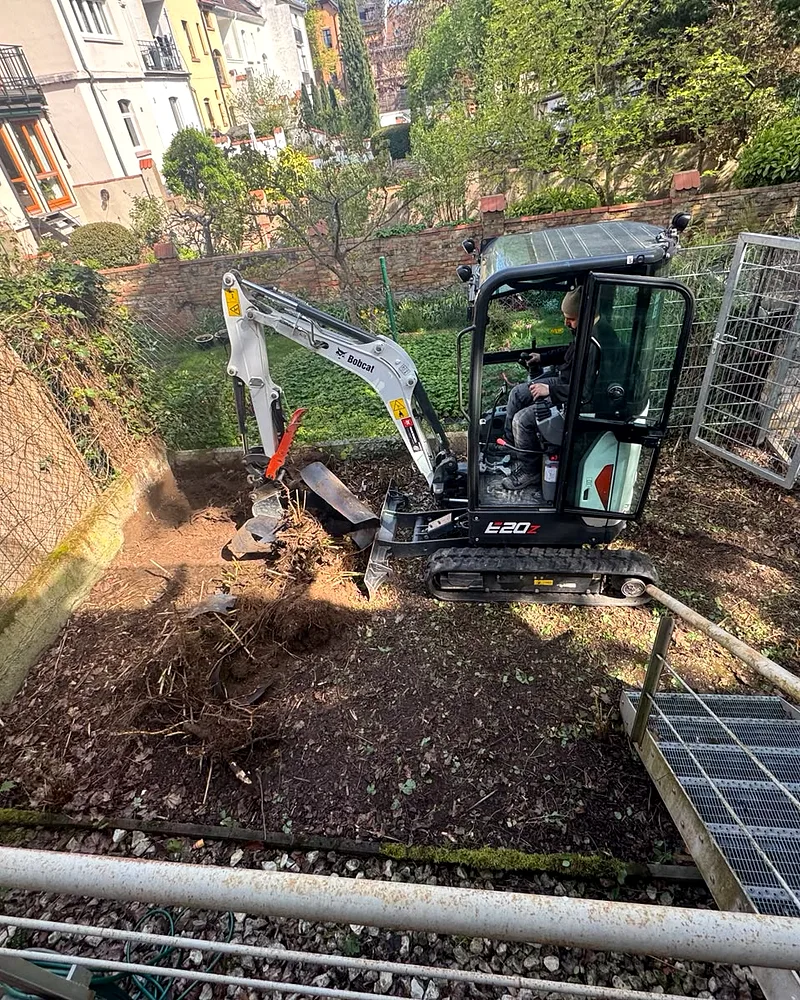Erdarbeiten in Worms: Minibagger (Bobcat E20z) beim Ausheben der Beetfläche im terrassierten Reihenhausgarten