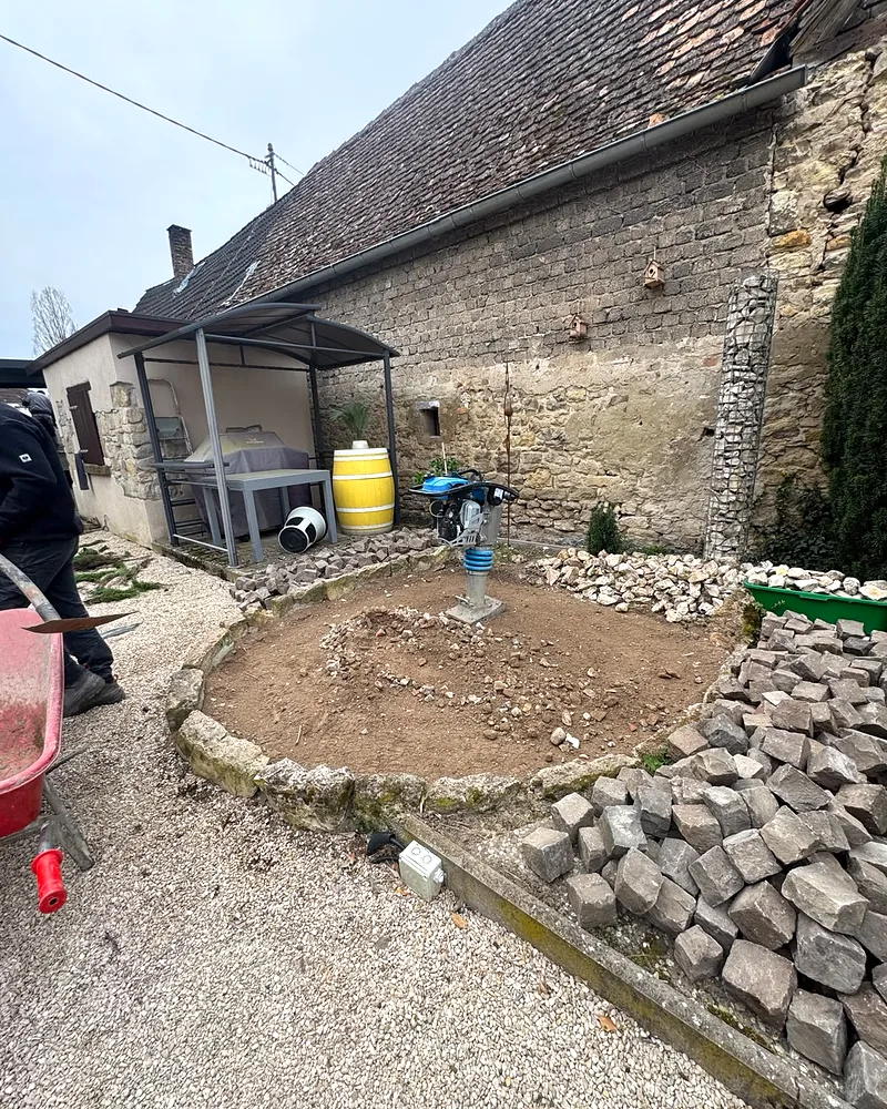 Innenhof eines Hofguts in Mainz mit kreisförmig vorbereitetem Erdbett, Vibrationsstampfer und bereitliegendem Naturstein-Kleinpflaster vor der Verlegung
