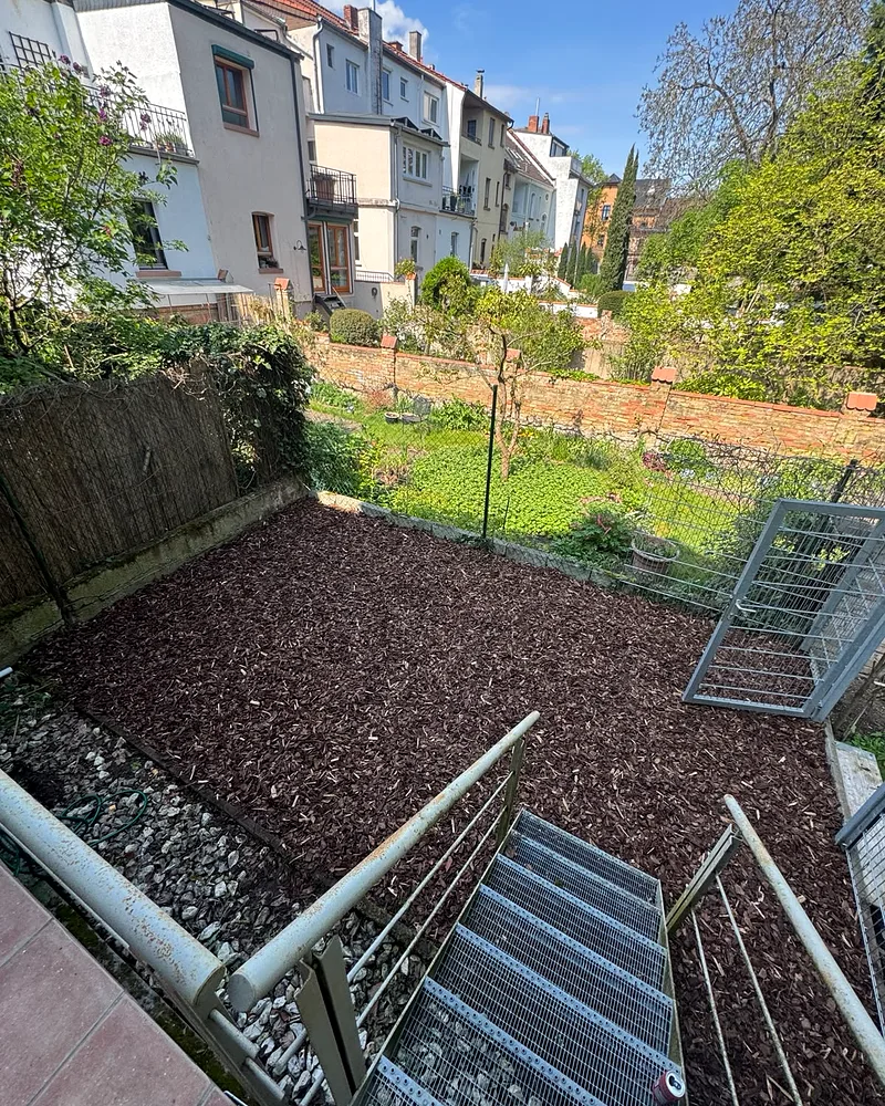 Garten in Worms nach der Gestaltung: neu angelegtes Beet mit braunem Rindenmulch im terrassierten Reihenhausgarten